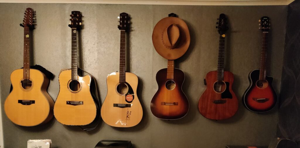 Sex gitarrer och en hatt på rad mot en vägg